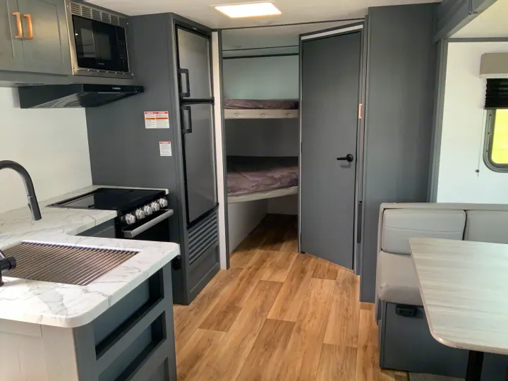 RV rental interior with a gray & white kitchen (stove, microwave, fridge), bunk beds, and dinette.. Keystone RV Bullet Crossfire 2022