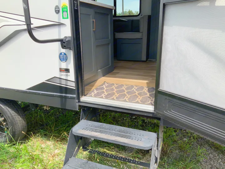 Step into adventure with this RV rental! View of the open entrance, steps, and interior of a modern travel trailer.. Keystone RV Bullet Crossfire 2022