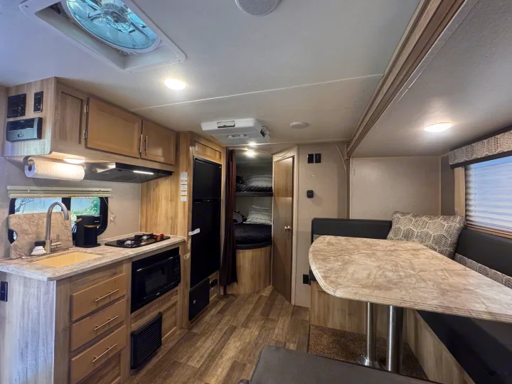 Spacious RV rental interior with a modern kitchen, dining area, and cozy bunk beds, ideal for family travel.. Coachmen 184BHS 2021