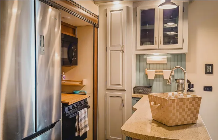 A functional kitchen in an RV rental, featuring a stainless steel fridge, microwave, stove, and sink. Perfect for mobile living.. Coachmen Chaparral 2018