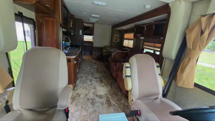 Experience comfort in this RV rental's inviting interior, featuring front seats, a well-equipped kitchen, and a cozy living area.. 1F65F5DY3E0A15748 Pursuit 31 BD 2015