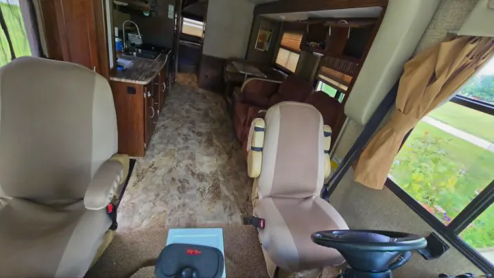 Spacious RV interior of this rv rental: view of driver/passenger seats, steering wheel, kitchen, and comfy living area.. 1F65F5DY3E0A15748 Pursuit 31 BD 2015