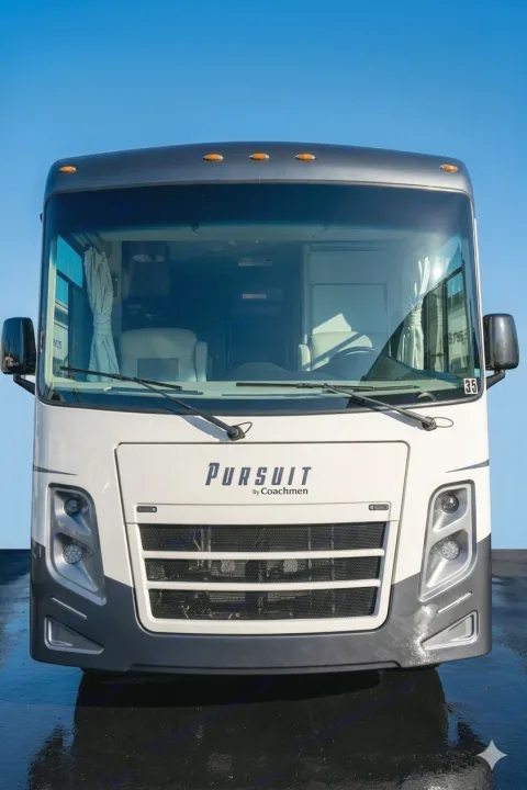 Front view of a sleek, white and grey Pursuit by Coachmen RV rental, parked under a blue sky, ready for your next adventure.. Coachmen Pursuit 2019