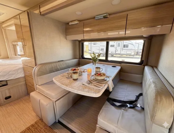 Modern RV rental dinette with breakfast laid out. Enjoy comfort and a view from this bright, inviting interior.. Thor Motor Coach Delano 2022