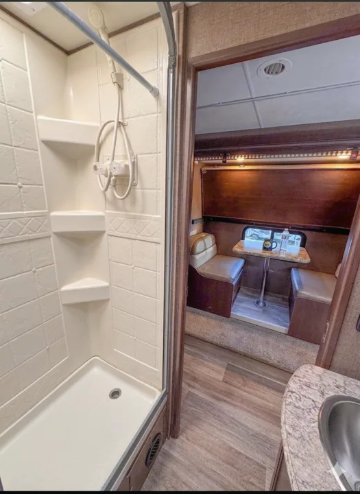 RV rental: Clean shower stall and a cozy dinette with bench seating and a table inside a recreational vehicle.. Thor Motor Coach 30d 2020
