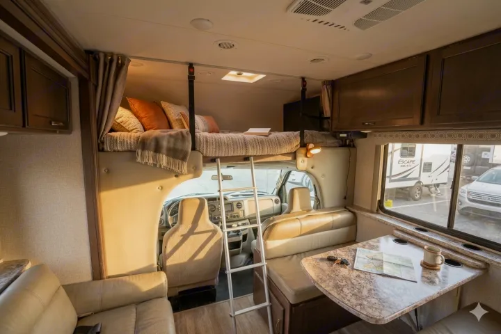 Cozy rv rental interior: overhead bed, ladder, dinette, and front cabin. Ideal for family road trip adventures.. Thor Motor Coach 30d 2020