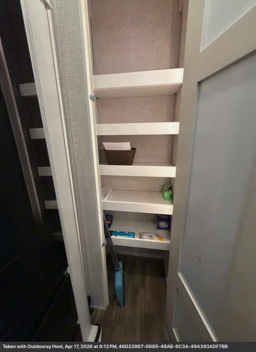 This RV rental features a well-organized pantry with shelves, a basket, and cleaning supplies for convenient mobile living.. Jayco Eagle 2025