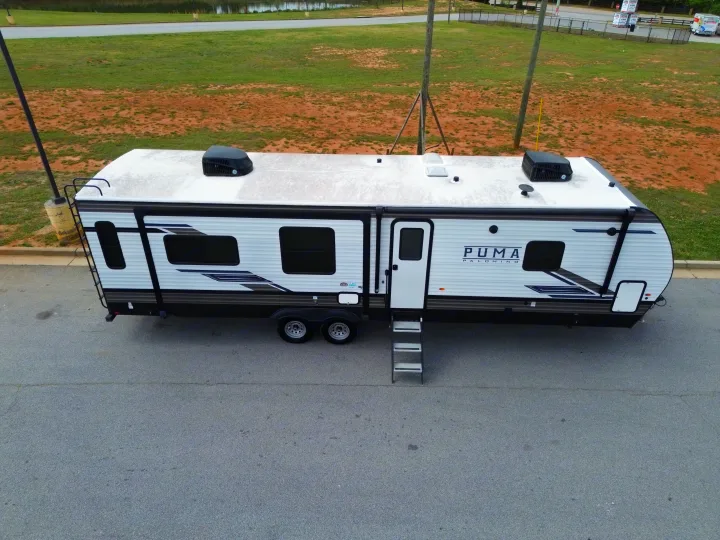 Aerial view of a white Puma Palomino rv rental travel trailer parked on asphalt, ready for a road trip adventure.. Forest River Puma 2023