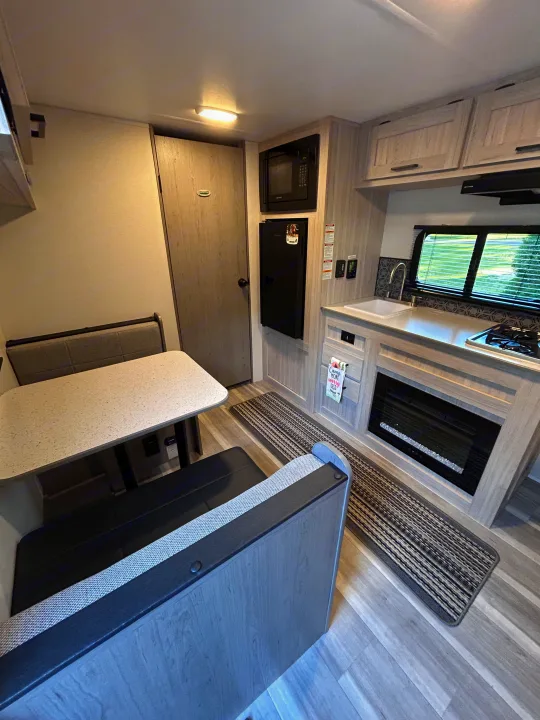 Modern RV rental interior featuring a compact kitchen, dinette, and fireplace. Ideal for comfortable travel.. Heartland RVs Pioneer 2025