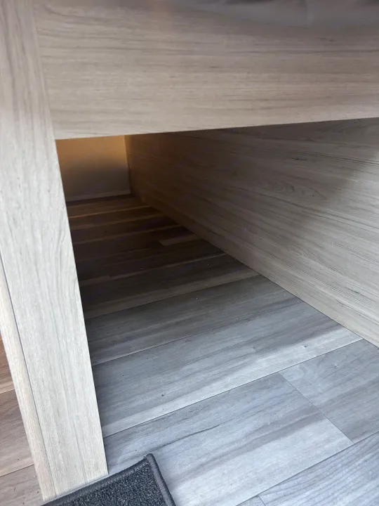 RV rental interior: view of the under-furniture storage area. Features gray wood-look flooring and light wood paneling.. Heartland RVs Pioneer 2025