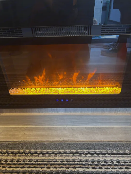 Cozy electric fireplace inside an RV rental, featuring glowing crystals and faux flames for a warm ambiance.. Heartland RVs Pioneer 2025
