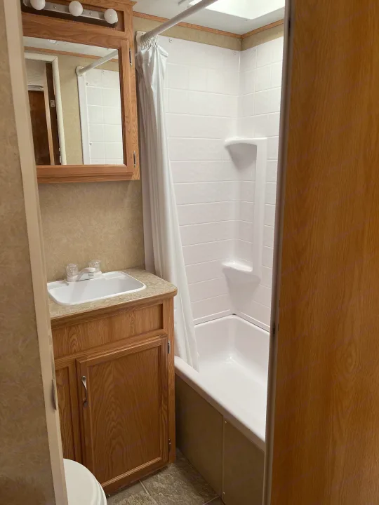 Clean RV rental bathroom with sink, mirrored vanity, and shower/tub combo. Essential travel amenities for your trip.. Crossroads RV Sunset Trail 2008