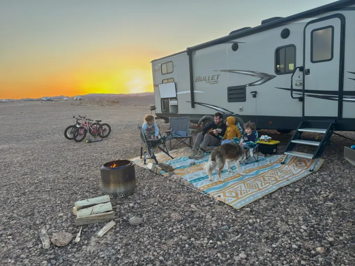 RV rental adventure: Family, dog, & campfire gather next to a Keystone Bullet RV against a beautiful desert sunset.. Keystone RV Bullet Ultra Lite 2021