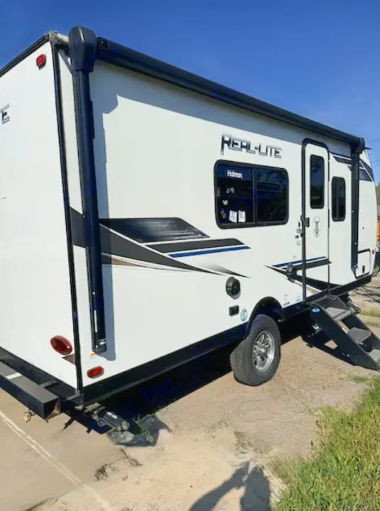 White REAL-LITE travel trailer RV rental, with steps & awning, parked outdoors on a sunny day.. Forest River Palomino Real-Lite Mini 2021