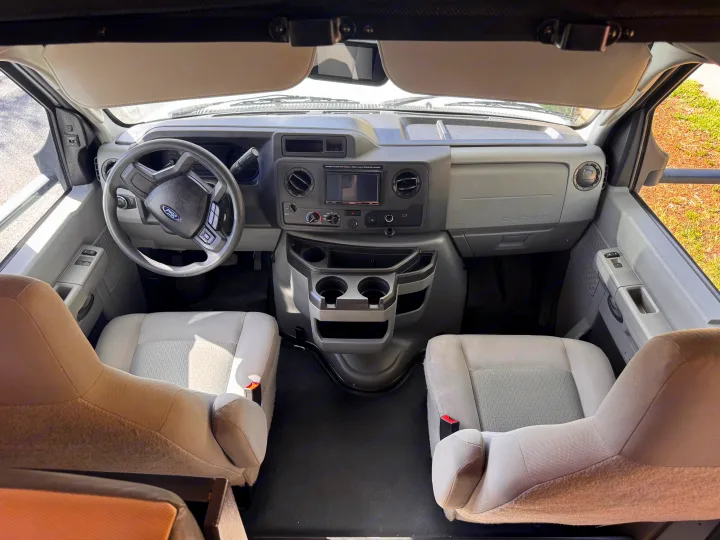 RV rental interior: cockpit with steering wheel, dashboard, center console, and front seats, viewed from above.. Forest River Sunseeker LE 2025