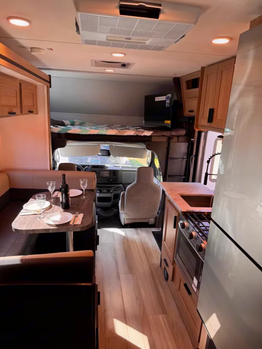 Cozy RV rental interior with kitchen, dining area, and cab-over bed visible. Ready for your road trip comfort.. Forest River Sunseeker LE 2025