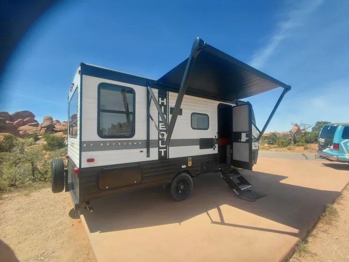 Keystone Hideout RV rental with an extended awning, parked on concrete in a scenic desert campsite with red rock formations.. Keystone RV Hideout 2022