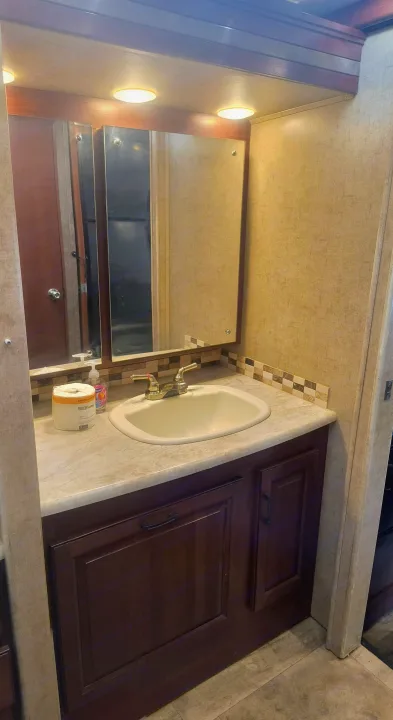 Compact RV rental bathroom vanity features a sink, mirror, and cabinets, providing essential amenities for your journey.. Forest River forester 2016