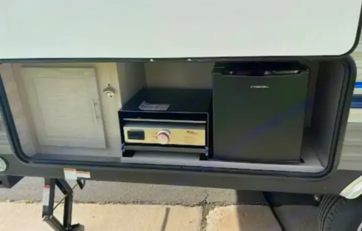 RV rental outdoor kitchen featuring a mini-fridge, compact grill, and a wall-mounted bottle opener.. Coachmen Catalina Summit 2022