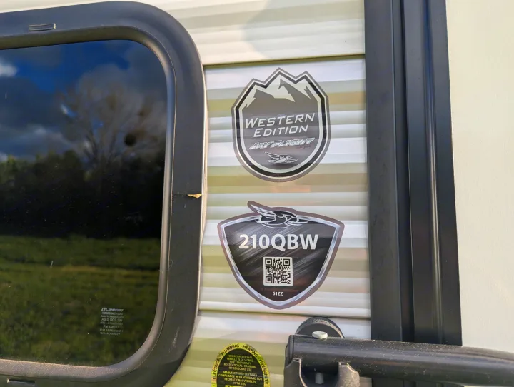 RV rental: Jay Flight Western Edition 210QBW model badges and a window with safety glass details are on its exterior.. Jayco Jay Flight SLX 2025