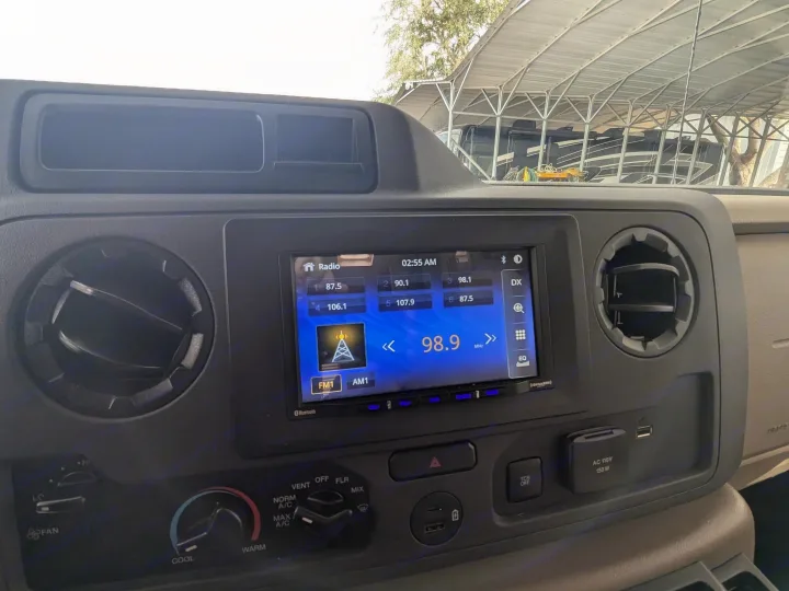 RV rental dashboard: modern digital radio (98.9 MHz), climate controls, and AC 110V/USB power outlets.. Thor Chateau 2025