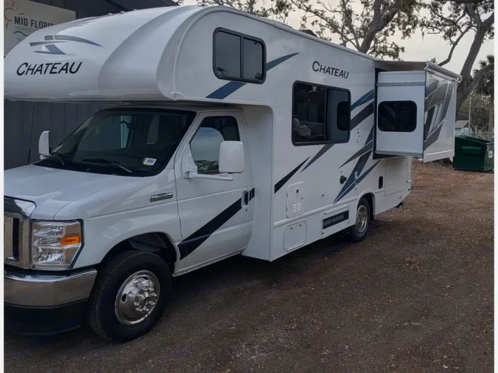 White Chateau Class C rv rental with its side slide-out extended, parked on gravel, ready for adventures.. Thor Chateau 2025