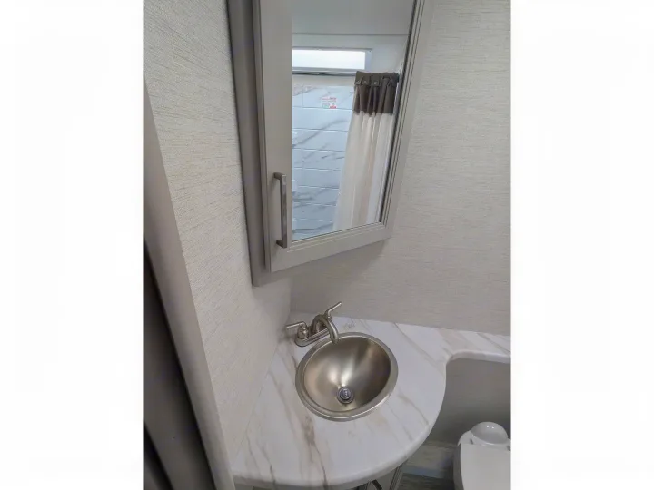 RV rental bathroom features a vanity, stainless sink, mirror, and a toilet. Shower visible in reflection.. Thor Chateau 2025