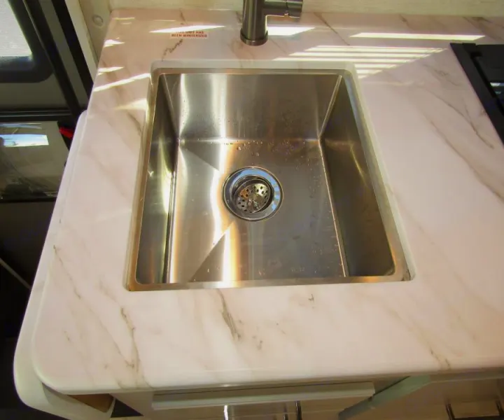 This RV rental features a clean stainless steel kitchen sink and white marble-look countertop with a modern faucet.. Thor Chateau 2025