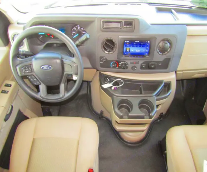 Detailed interior of an RV rental: driver's cockpit with steering wheel, dashboard, infotainment, and cup holders, ready for your adventure.. Thor Chateau 2025