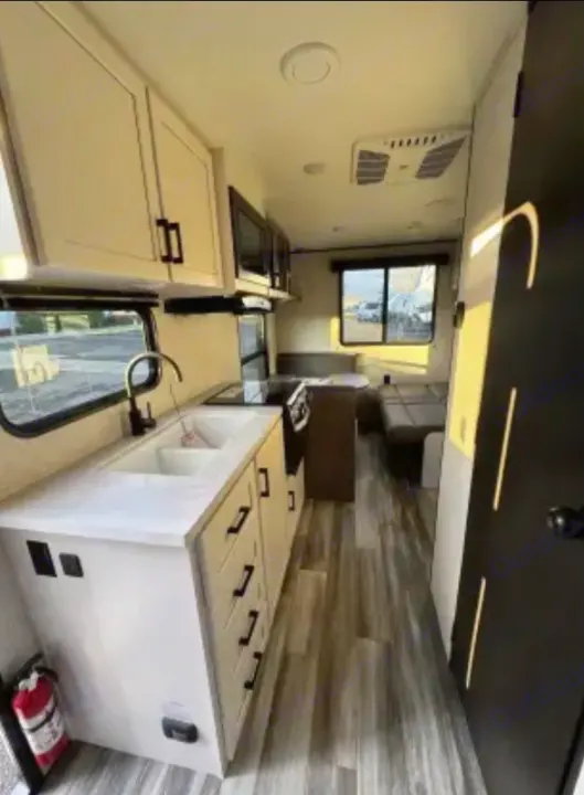 Bright rv rental interior: modern kitchen with double sink, stove, and dinette seating. Clean and ready for travel.. Jayco Jay Flight SLX 2025