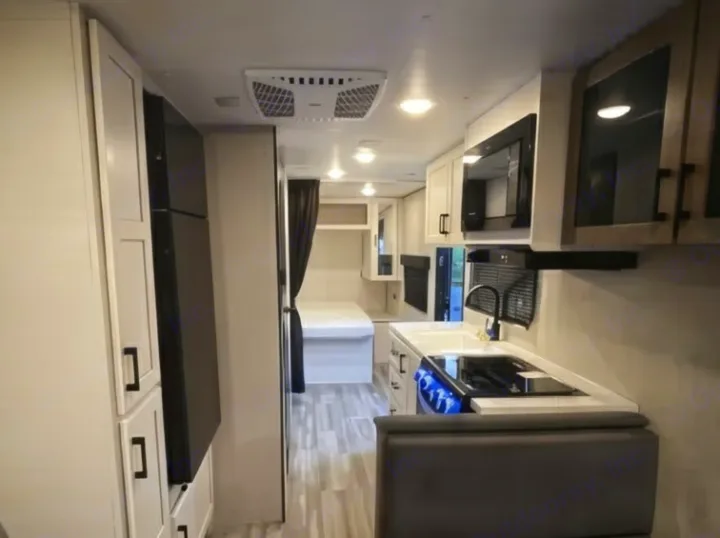 This clean RV rental interior boasts a full kitchen with microwave, fridge, and a bright, inviting bedroom space.. Jayco Jay Flight SLX 2025