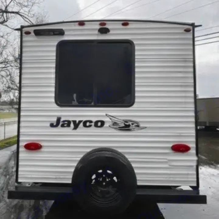 Rear view of a white Jayco travel trailer for rv rental, showing the spare tire, window, and taillights.. Jayco Jay Flight SLX 2025