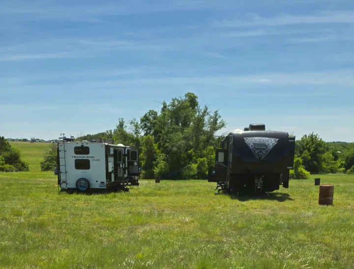 Spacious field setup with two RV rentals: a white Transcend Xplor and a dark Vengeance travel trailer.. Grand Design Transcend Xplor 2024