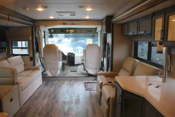 Spacious rv rental interior showing driver's area, lounge seating, and kitchenette, ideal for travel.. Thor Motor Coach INDIGO - CC35 2024
