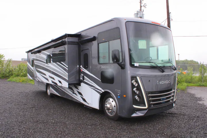 Gray Thor Indigo RV rental, with slide-out and awning extended, parked on a gravel lot under an overcast sky.. Thor Motor Coach INDIGO - CC35 2024