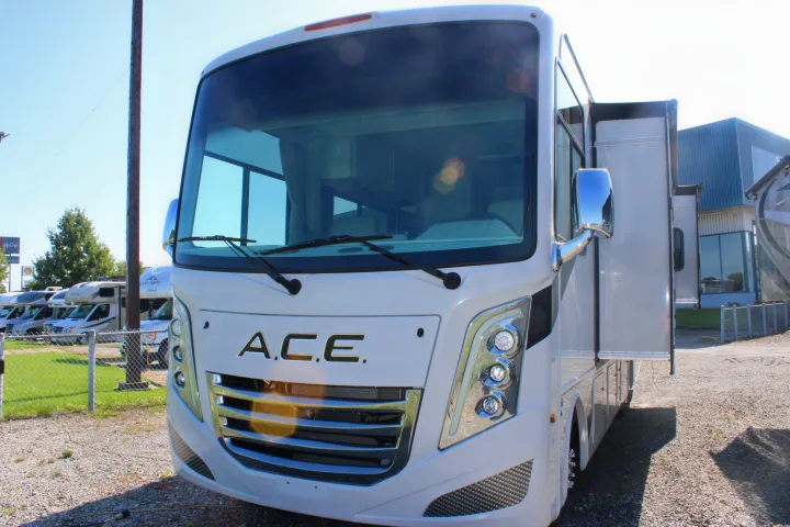 A gleaming white Thor A.C.E. Class A RV rental is parked, showing its prominent front grille, headlights, and windshield.. Thor Motor Coach Ace 2024
