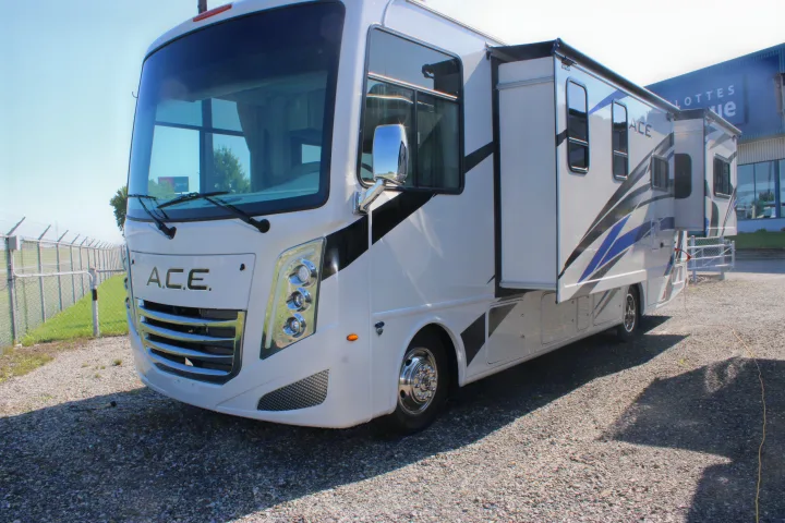 White A.C.E. motorhome RV rental parked on gravel with its slide-out extended on a sunny day.. Thor Motor Coach Ace 2024