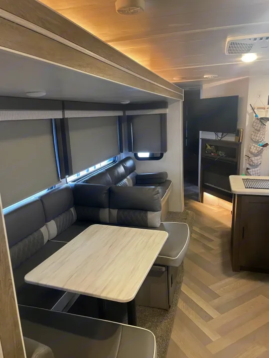 Comfortable RV rental living area featuring a gray U-shaped dinette, entertainment center, and herringbone flooring.. Forest River Salem 2022