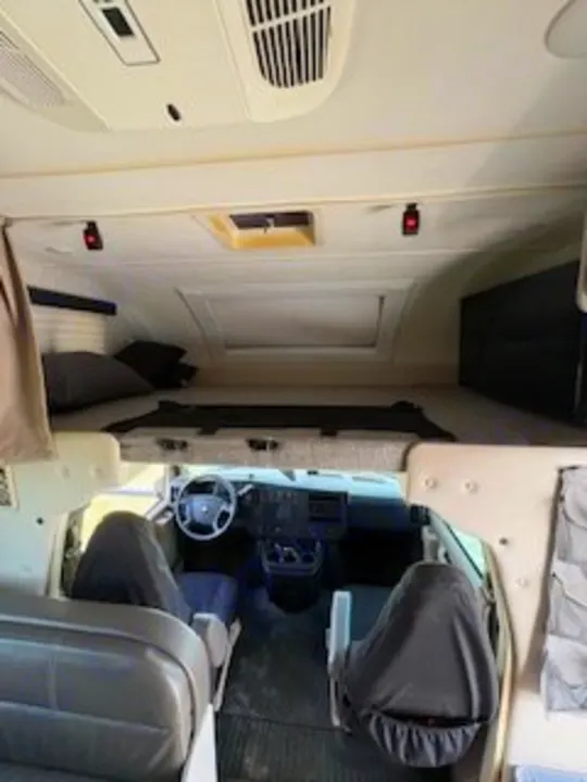Inside this RV rental, view the front cab with covered seats and a spacious over-cab bunk. Ready for your adventure!. Thor Quantum LC 2022