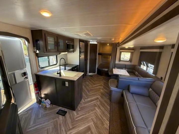 Spacious rv rental interior featuring a modern kitchen, L-shaped seating, and bunk beds for family travel.. Forest River Salem 2022