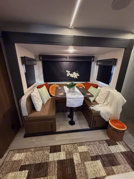 Enjoy this inviting RV rental dinette with U-shaped seating, plush pillows, and a table with floral decor.. Forest River Wildcat One 241DBEDS 2026