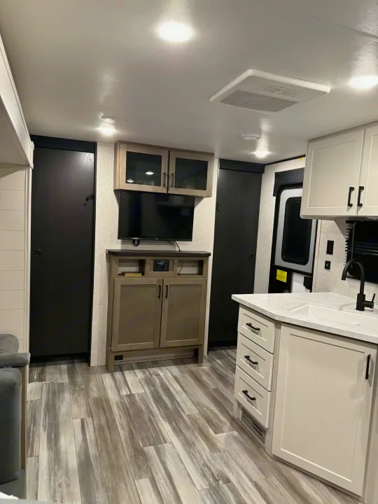 Modern RV rental interior: A compact kitchen, living area with TV, ample storage, and wood-look flooring.. Jayco Jay Flight SLX 2025