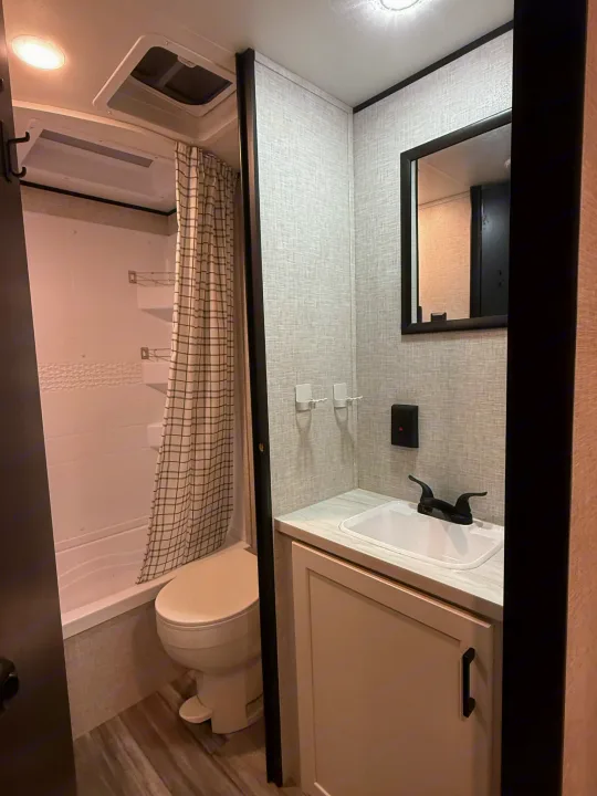 RV rental bathroom with compact shower, toilet, sink, vanity, and mirror. Modern design for travel comfort.. Jayco Jay Flight SLX 2025