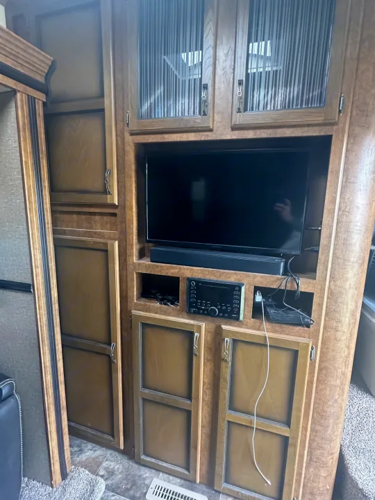 This RV rental interior features a built-in entertainment system with TV, soundbar, and multiple storage cabinets.. Crossroads RV Rezerve 2016