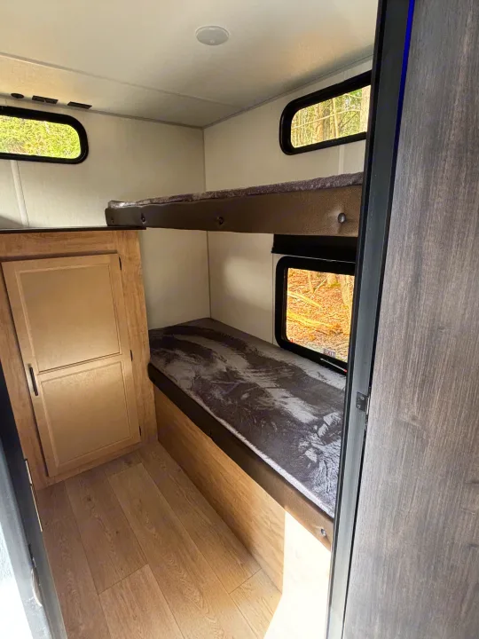 Cozy rv rental interior with stacked bunk beds, individual windows, and a built-in storage cabinet.. Forest River Cherokee Grey Wolf 29TE 2026
