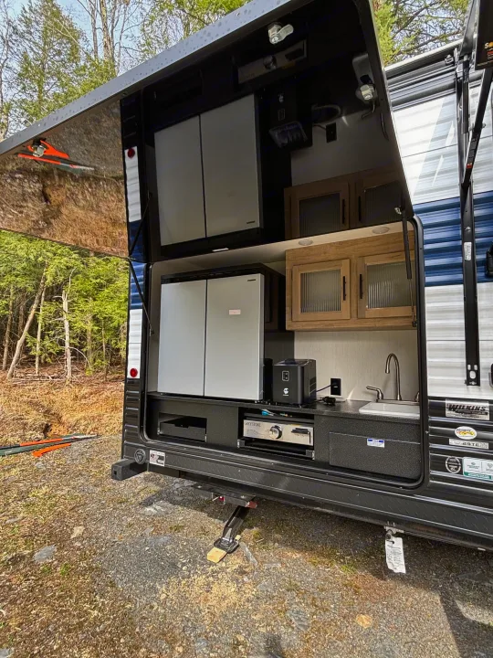This RV rental's outdoor kitchen on a travel trailer includes a fridge, sink, and cooktop, ideal for outdoor cooking.. Forest River Cherokee Grey Wolf 29TE 2026