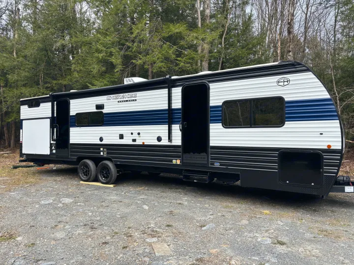RV rental: A white and blue Cherokee Grey Wolf travel trailer parked on gravel in a wooded area with open doors.. Forest River Cherokee Grey Wolf 29TE 2026