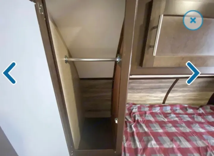 RV rental: Compact bedroom closet with a hanging rod, next to a bed with a red plaid comforter.. Forest River Cherokee 2018