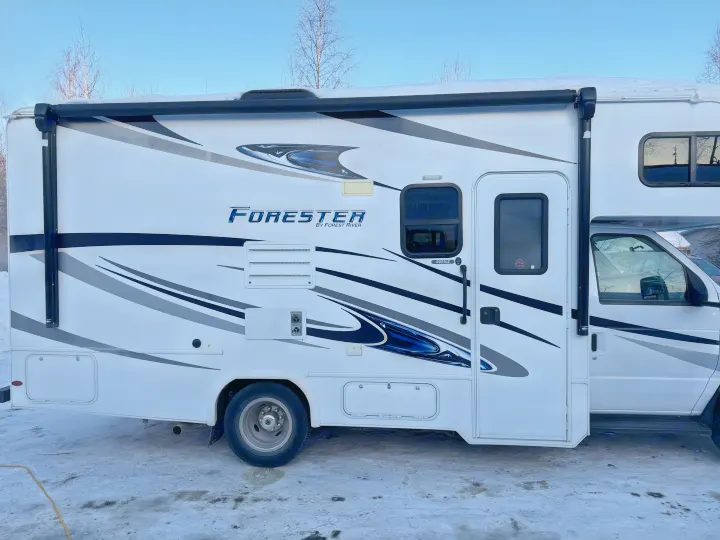 Side view of a white Forester Class C motorhome, an ideal RV rental. Features black/grey graphics, parked in snow for winter travel.. Forester Forester Motorhome 2020