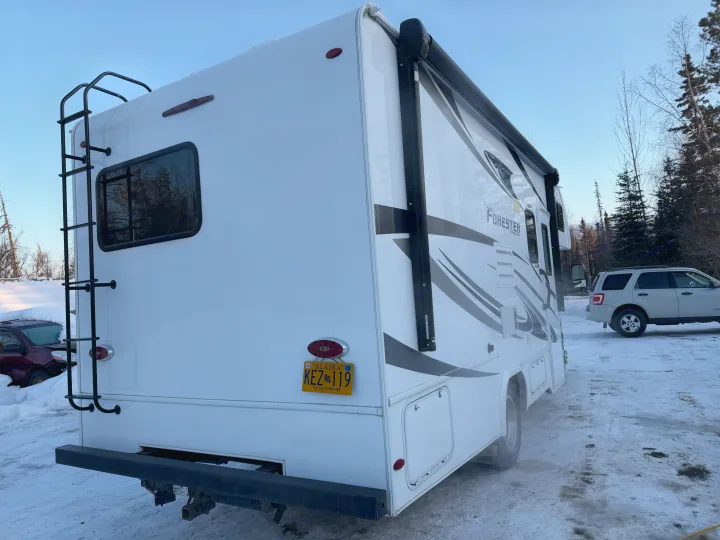 White rv rental with an Alaska plate (KEZ 119) and ladder, parked in a snowy setting with trees.. Forester Forester Motorhome 2020